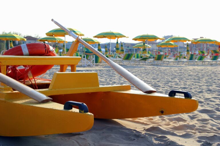 Travel to Rimini, Italy. The catamaran on the foreground on the empty beach with a lot of sunbeds and umbrellas on the background.